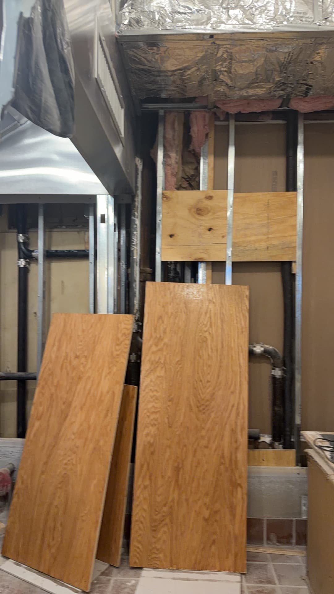 Steel framing and ductwork mid-buildout, with flooring materials staged